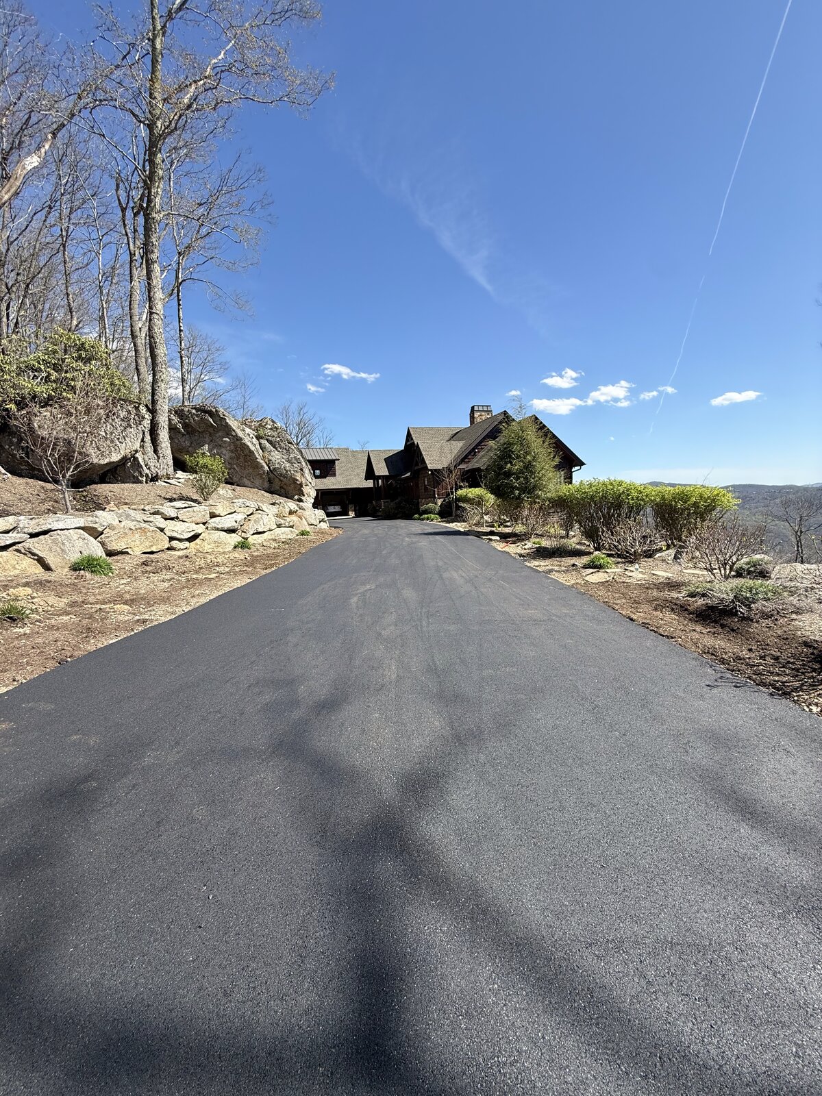 Freshly paved mountain driveway leading to a rustic home